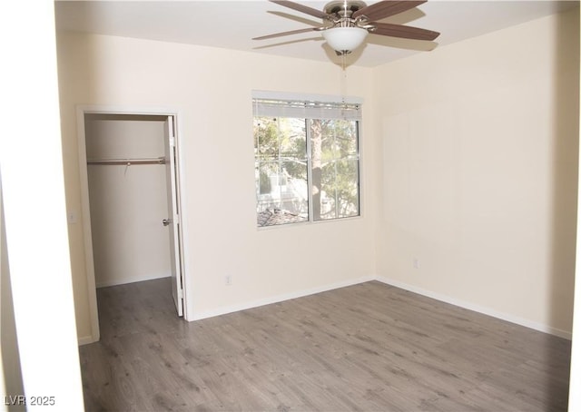 unfurnished bedroom featuring ceiling fan, a spacious closet, a closet, and dark hardwood / wood-style flooring