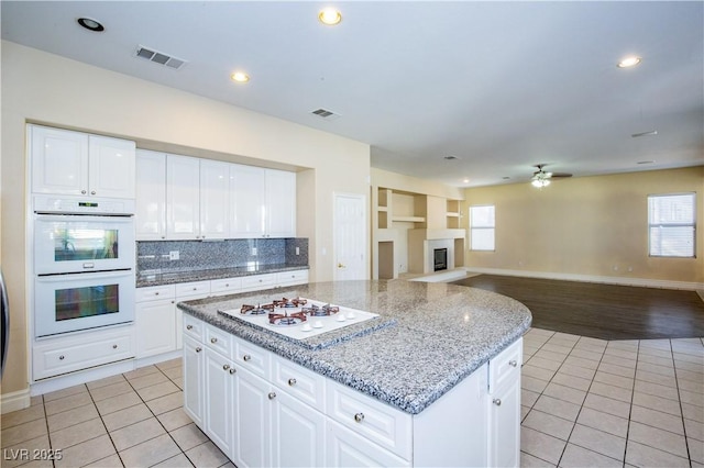 kitchen featuring white cabinetry, white appliances, light tile patterned floors, and a center island