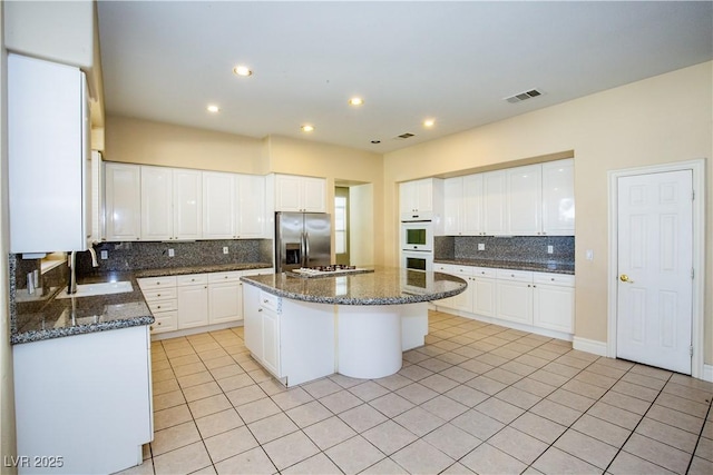 kitchen featuring a center island, white appliances, white cabinetry, light tile patterned floors, and sink