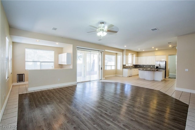 unfurnished living room featuring light tile patterned floors and ceiling fan