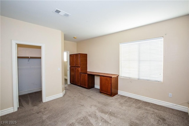 unfurnished bedroom featuring a spacious closet, light colored carpet, and a closet