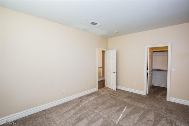 unfurnished bedroom with carpet floors, a closet, and a walk in closet