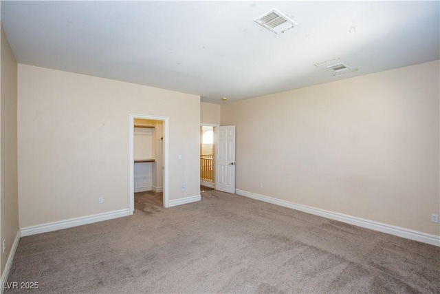 unfurnished bedroom featuring a walk in closet, light carpet, and a closet