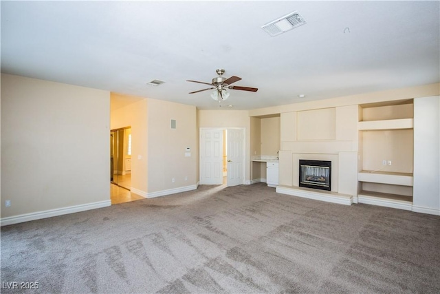 unfurnished living room with ceiling fan, light colored carpet, and built in features