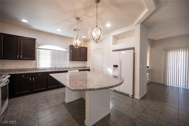 kitchen featuring a center island, a sink, dark brown cabinets, white fridge with ice dispenser, and plenty of natural light