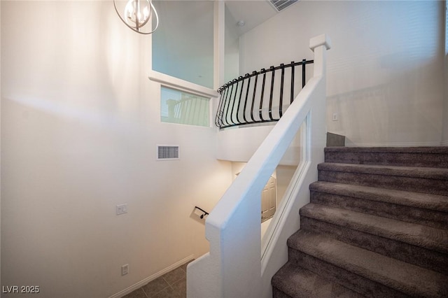 stairs featuring visible vents, baseboards, and an inviting chandelier