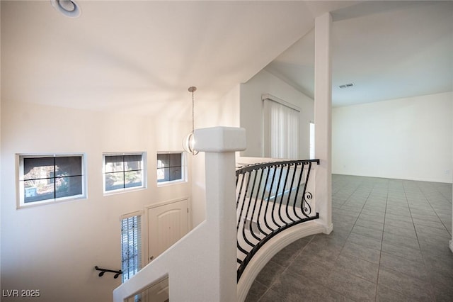 hallway with tile patterned flooring, visible vents, and an upstairs landing