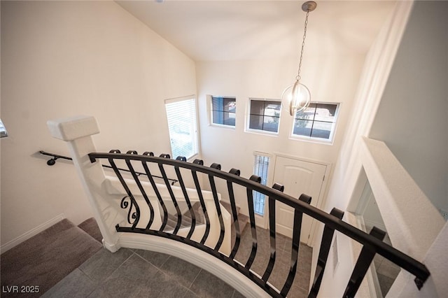 stairs featuring baseboards, a chandelier, and a towering ceiling