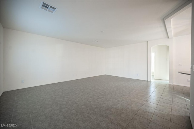 unfurnished room featuring visible vents and arched walkways