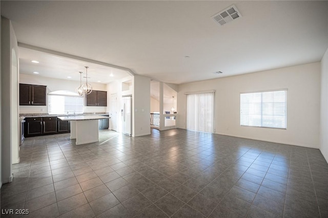 unfurnished living room featuring a chandelier, recessed lighting, visible vents, and dark tile patterned floors