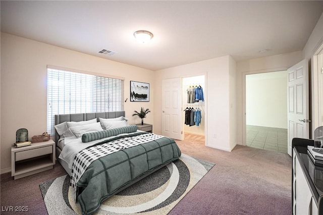 carpeted bedroom featuring a walk in closet, baseboards, visible vents, and a closet