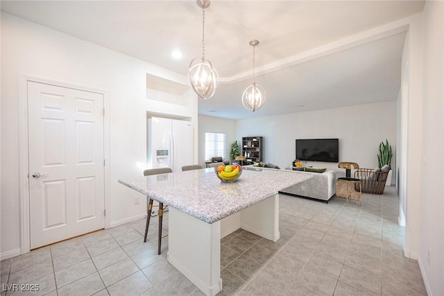 kitchen featuring decorative light fixtures, a kitchen breakfast bar, a center island, light tile patterned floors, and light stone countertops