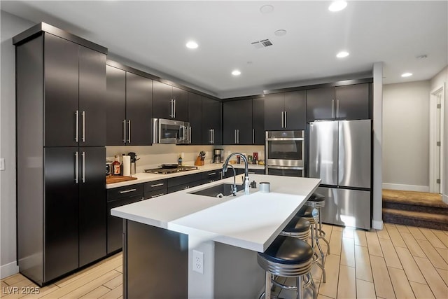 kitchen featuring an island with sink, a kitchen bar, sink, and stainless steel appliances