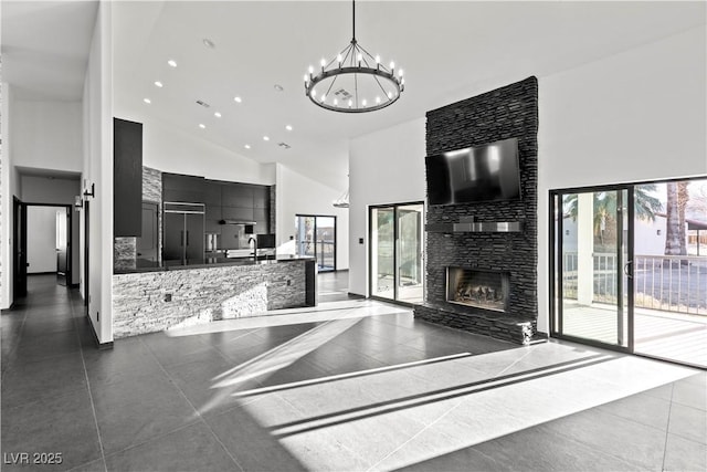 kitchen with decorative light fixtures, a fireplace, dark tile patterned floors, high vaulted ceiling, and paneled refrigerator