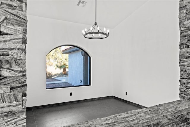 tiled empty room featuring a notable chandelier