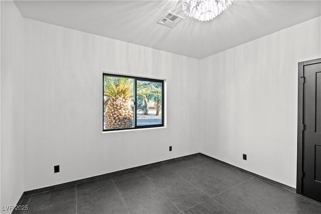 tiled empty room featuring a notable chandelier