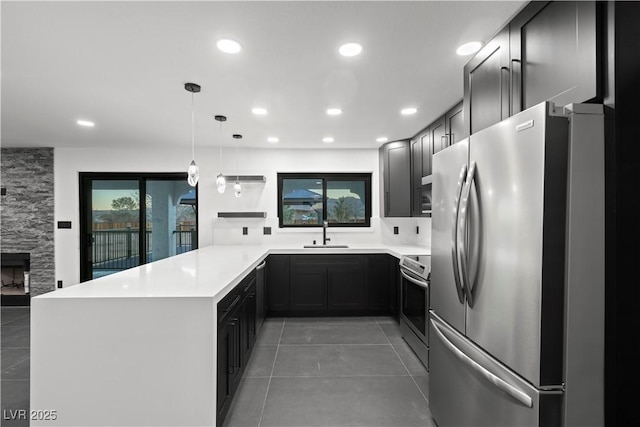 kitchen with a fireplace, pendant lighting, kitchen peninsula, sink, and appliances with stainless steel finishes