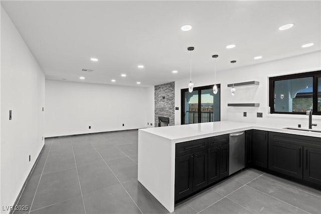 kitchen featuring decorative light fixtures, a fireplace, kitchen peninsula, sink, and light tile patterned floors