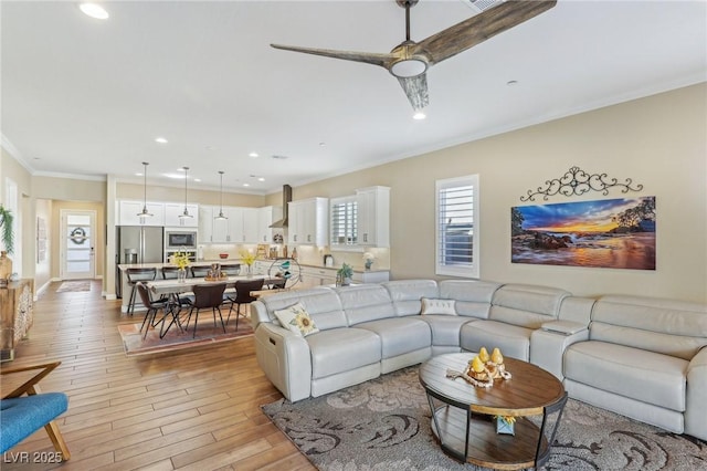 living room with ceiling fan, ornamental molding, and light hardwood / wood-style floors