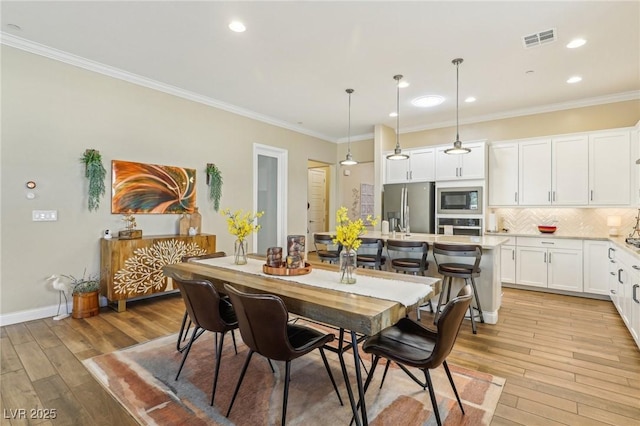 dining room featuring light wood-type flooring and ornamental molding