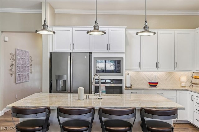 kitchen with a kitchen bar, stainless steel fridge, light stone countertops, white cabinets, and a center island