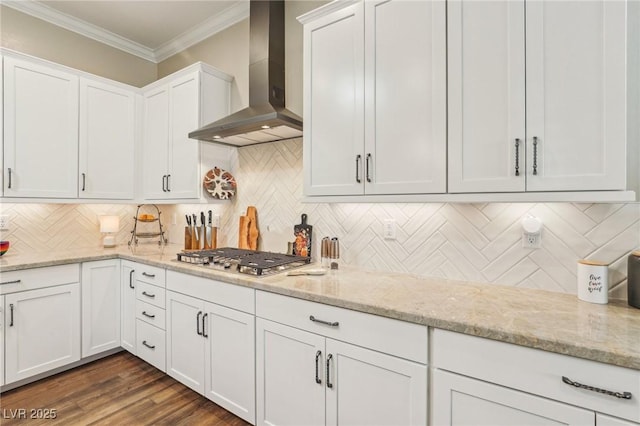 kitchen with white cabinets, wall chimney range hood, backsplash, ornamental molding, and stainless steel gas stovetop