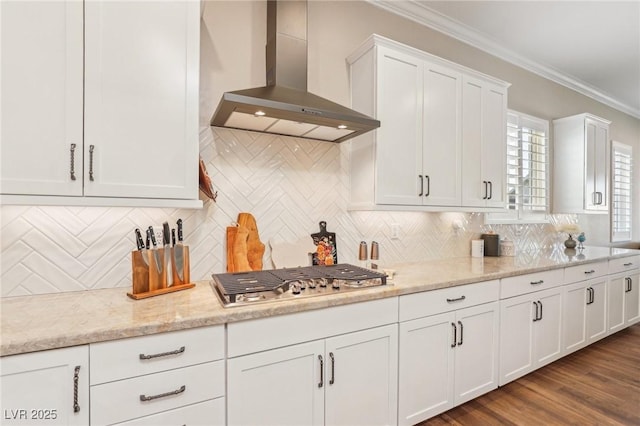 kitchen with white cabinets, wall chimney exhaust hood, backsplash, ornamental molding, and stainless steel gas stovetop