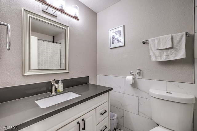 bathroom with tile walls, toilet, and vanity