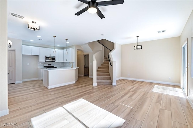 kitchen with ceiling fan, light hardwood / wood-style floors, white cabinets, decorative light fixtures, and stainless steel appliances