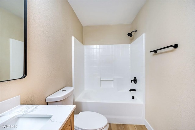 full bathroom with vanity, hardwood / wood-style flooring, washtub / shower combination, and toilet