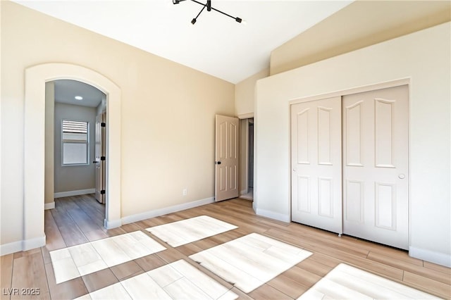 unfurnished bedroom with a closet, vaulted ceiling, and light wood-type flooring