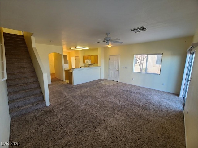 unfurnished living room featuring ceiling fan and carpet