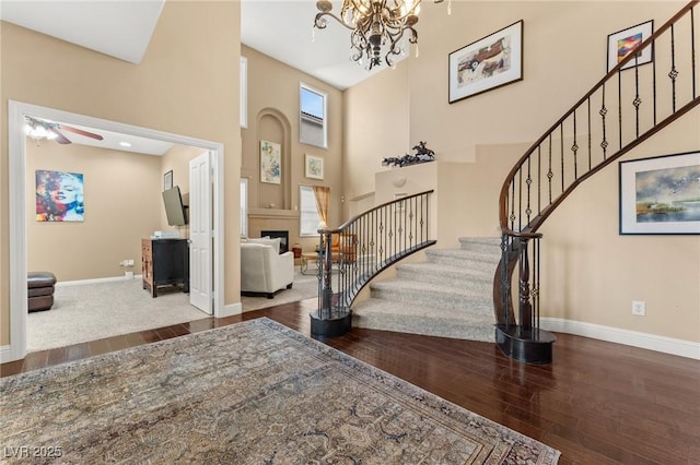 foyer entrance featuring plenty of natural light, a towering ceiling, hardwood / wood-style floors, and a notable chandelier