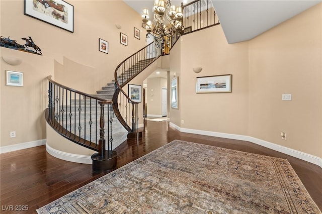 stairs featuring a notable chandelier, hardwood / wood-style floors, and a high ceiling