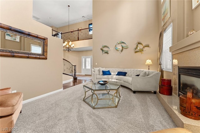 carpeted living room featuring a notable chandelier, a fireplace, and a high ceiling