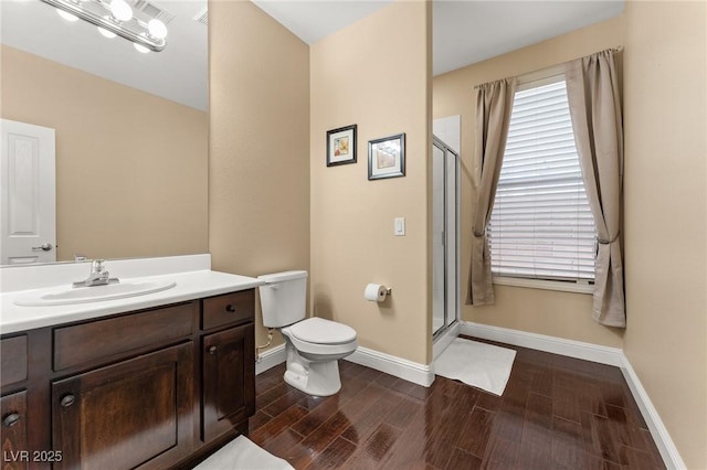 bathroom featuring a shower with door, vanity, and toilet