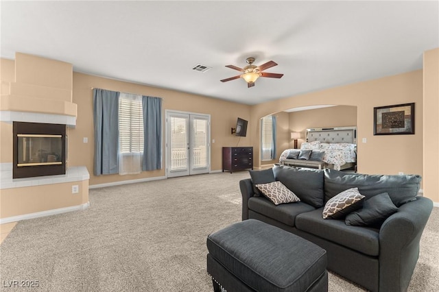 carpeted living room with a large fireplace and ceiling fan