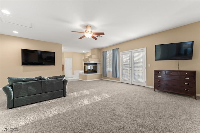 carpeted living room with ceiling fan and a multi sided fireplace