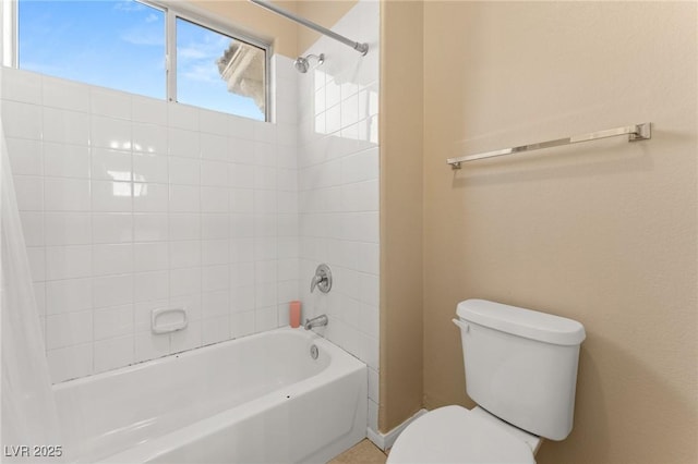 bathroom featuring tiled shower / bath combo and toilet