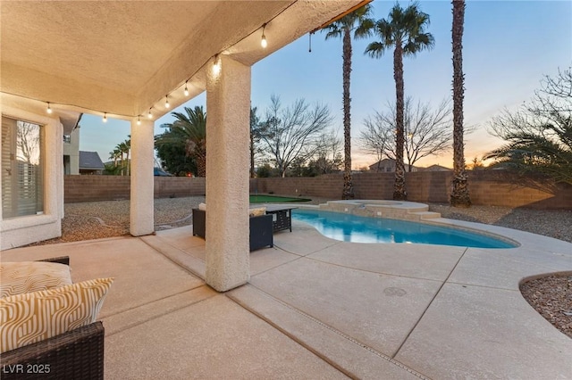 pool at dusk with a patio area and an in ground hot tub