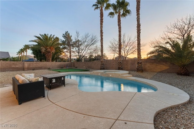 pool at dusk featuring a patio and an in ground hot tub