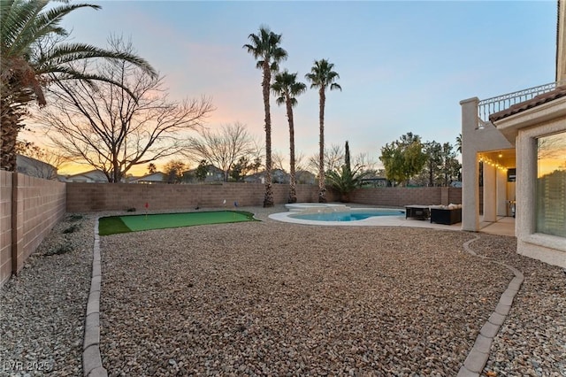 yard at dusk with a fenced in pool and a patio