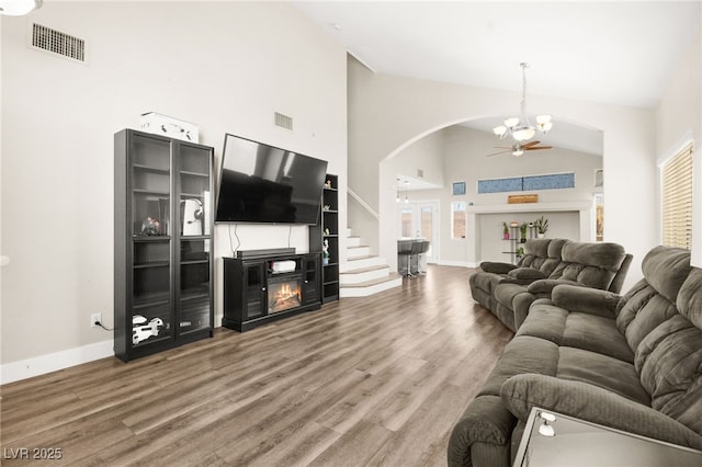 living room featuring high vaulted ceiling, a fireplace, ceiling fan with notable chandelier, and hardwood / wood-style flooring