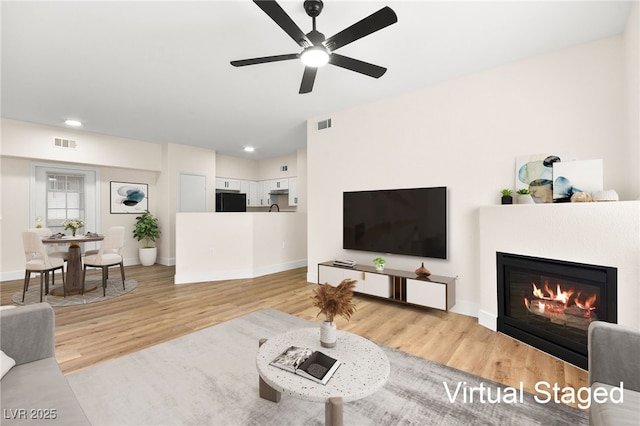 living room with ceiling fan and light hardwood / wood-style flooring