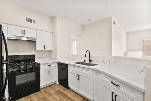 kitchen with black appliances, sink, light hardwood / wood-style flooring, white cabinets, and light stone counters