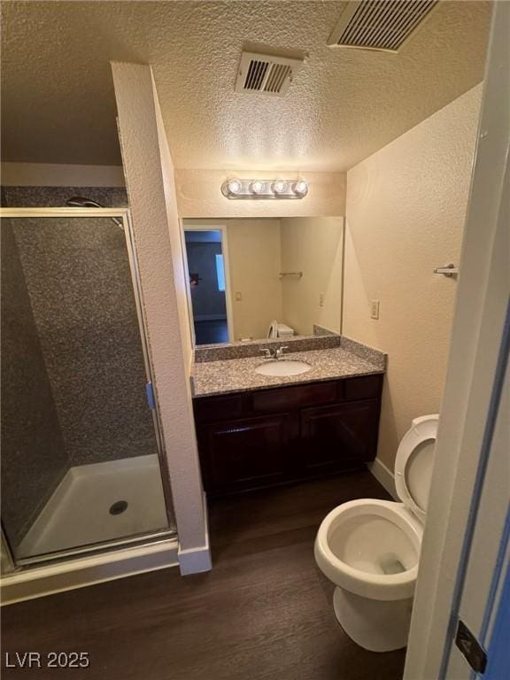 bathroom with hardwood / wood-style flooring, vanity, a shower with door, and toilet