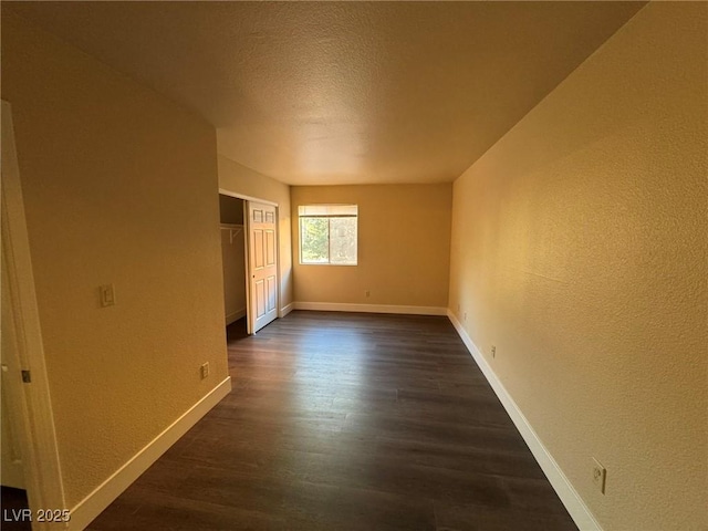 unfurnished room with dark hardwood / wood-style flooring and a textured ceiling