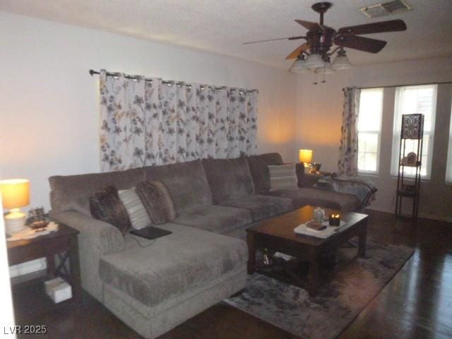 living room featuring dark wood-type flooring and ceiling fan