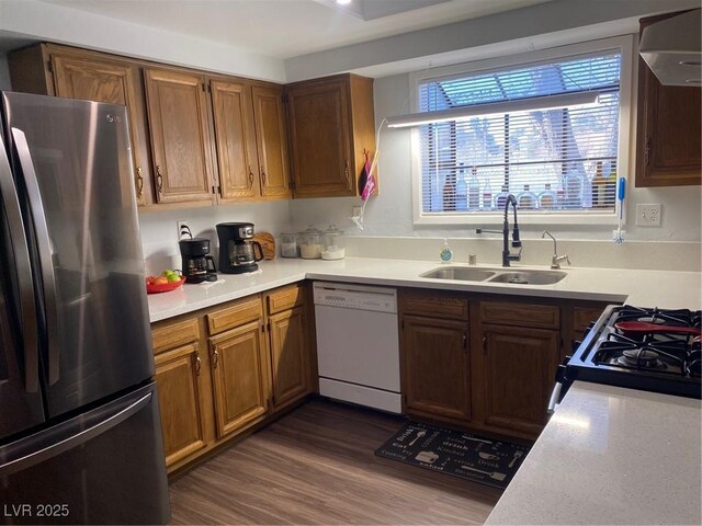 kitchen with sink, wall chimney range hood, stainless steel fridge, white dishwasher, and range with gas cooktop