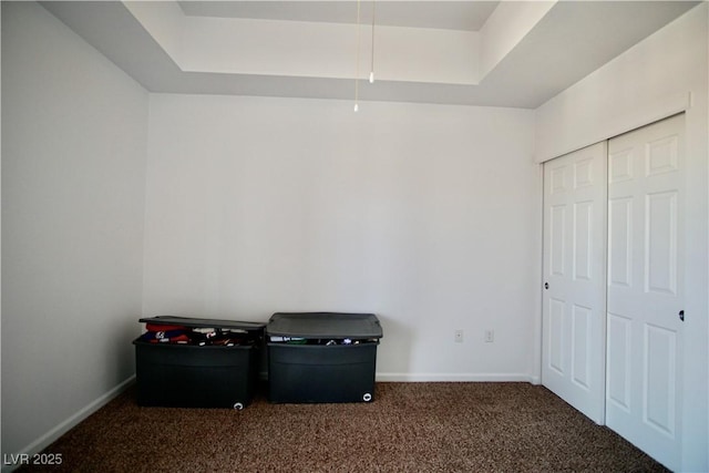 interior space with carpet floors and a tray ceiling